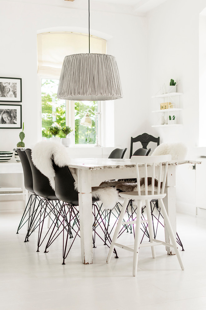 This is an example of a scandinavian open plan dining with white walls, no fireplace and white floor.