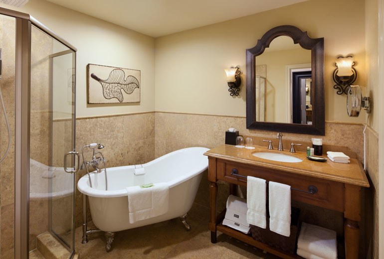Inspiration for a mid-sized mediterranean master bathroom in Sacramento with furniture-like cabinets, medium wood cabinets, a claw-foot tub, a corner shower, brown tile, porcelain tile, beige walls, porcelain floors, an undermount sink, wood benchtops, brown floor and a hinged shower door.