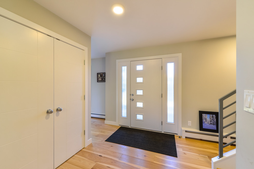 Example of a mid-sized minimalist light wood floor and beige floor foyer design in Calgary with beige walls and a white front door
