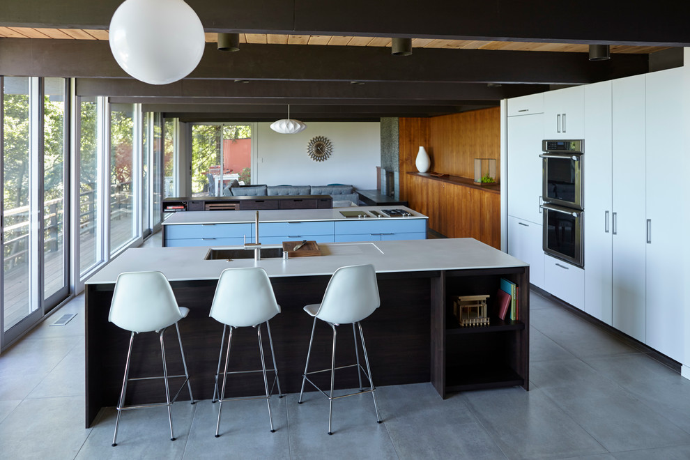 Photo of a mid-sized midcentury open plan kitchen in San Francisco with flat-panel cabinets, dark wood cabinets, solid surface benchtops, ceramic floors and multiple islands.