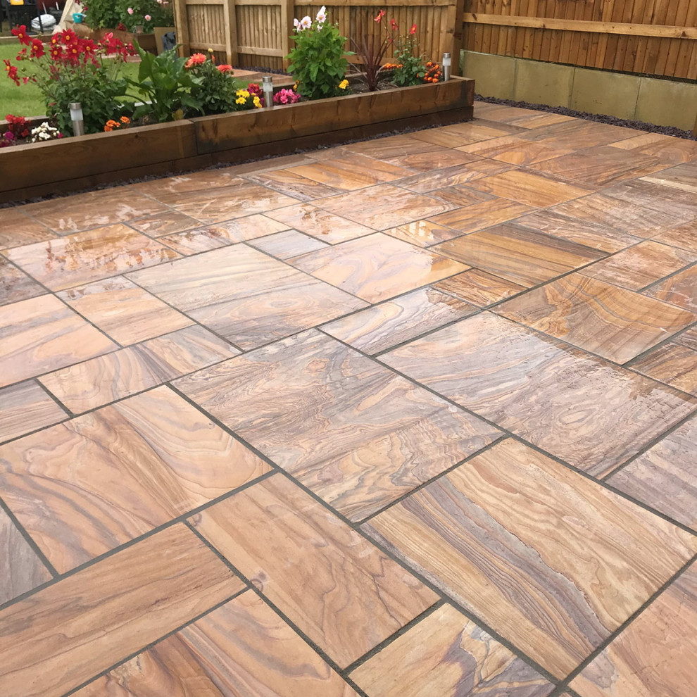 Medium sized contemporary back patio in Hertfordshire with natural stone paving.