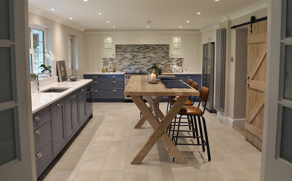 Photo of a transitional kitchen in London with an undermount sink, recessed-panel cabinets, blue cabinets, matchstick tile splashback, stainless steel appliances and no island.