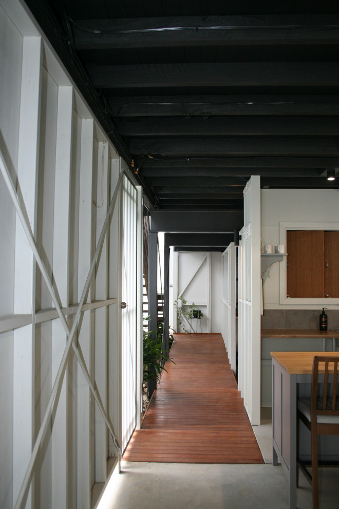 Foto di un corridoio moderno di medie dimensioni con pareti bianche, pavimento in legno massello medio, una porta bianca, pavimento marrone, boiserie, una porta singola e travi a vista