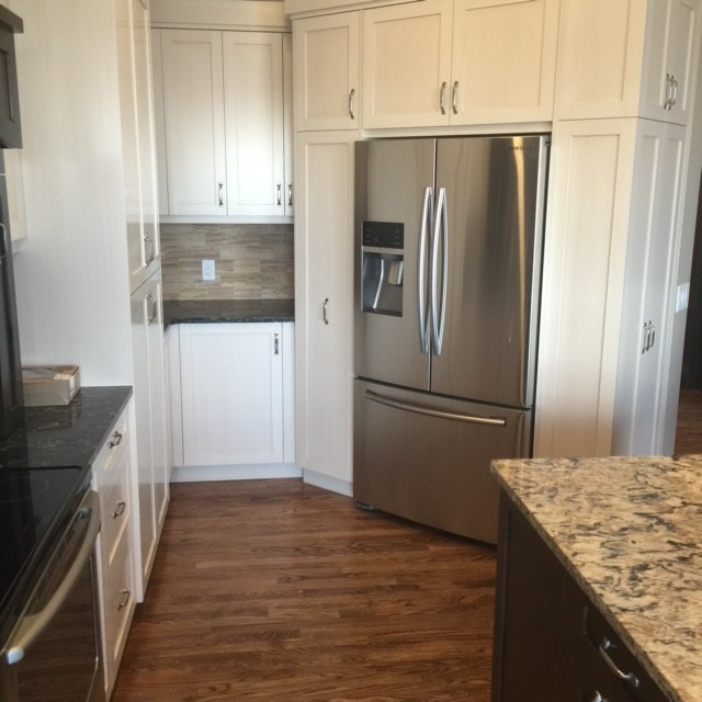 Eat-in kitchen - transitional medium tone wood floor eat-in kitchen idea in Calgary with shaker cabinets, black cabinets, granite countertops and an island
