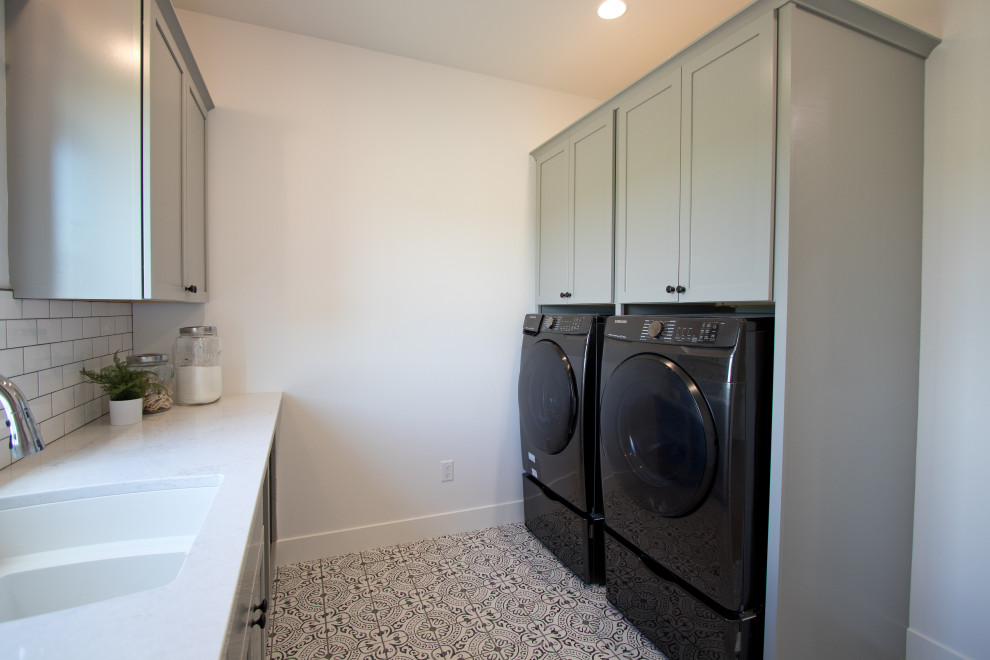 Galley dedicated laundry room in Other with an undermount sink, recessed-panel cabinets, grey cabinets, quartz benchtops, white splashback, white walls, porcelain floors, a side-by-side washer and dryer, multi-coloured floor and white benchtop.
