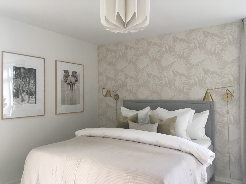 Diseño de dormitorio principal tropical grande con paredes beige, suelo de madera clara y papel pintado