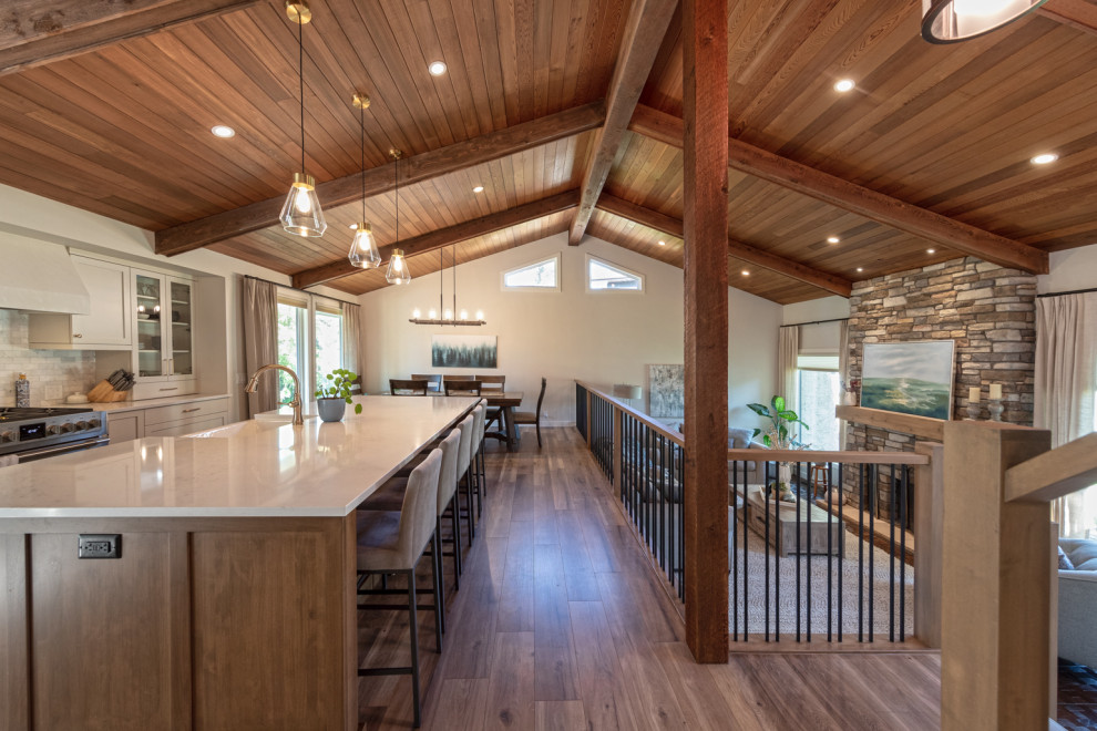 Mittelgroßes Country Wohnzimmer im Loft-Stil mit weißer Wandfarbe, hellem Holzboden, Kamin, Kaminumrandung aus gestapelten Steinen, braunem Boden und freigelegten Dachbalken in Edmonton