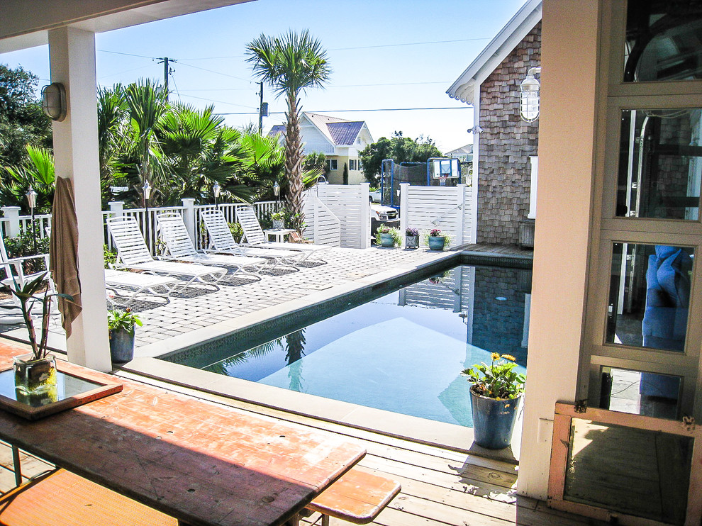 This is an example of a large beach style courtyard rectangular natural pool in Charleston with concrete pavers.