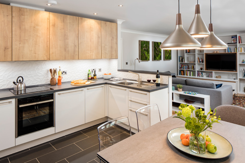 Mid-sized contemporary u-shaped open plan kitchen in Dublin with an integrated sink, flat-panel cabinets, light wood cabinets, laminate benchtops, white splashback, ceramic splashback, stainless steel appliances, ceramic floors and no island.