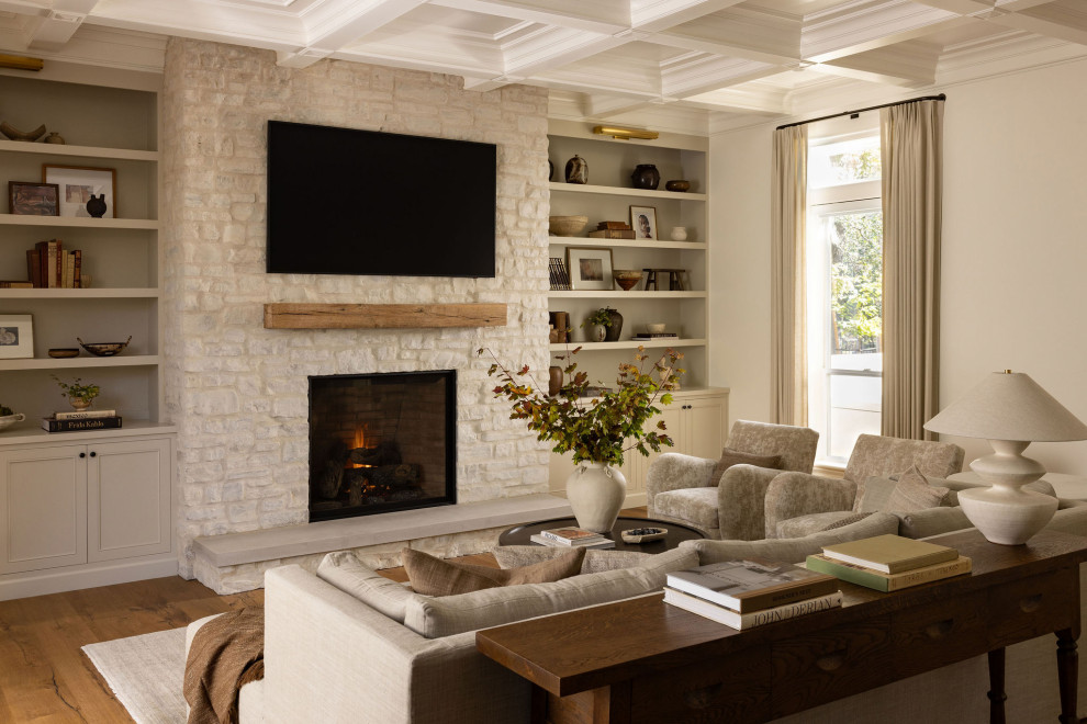 Transitional living room in Sacramento with beige walls, medium hardwood floors, a standard fireplace, a stone fireplace surround, a wall-mounted tv, brown floor and coffered.