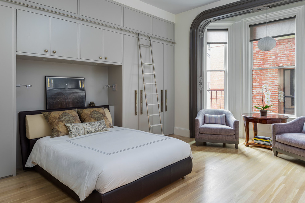 Example of a trendy light wood floor and beige floor bedroom design in Boston with white walls