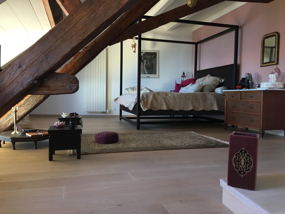 Photo of a contemporary master bedroom in Other with pink walls and light hardwood floors.