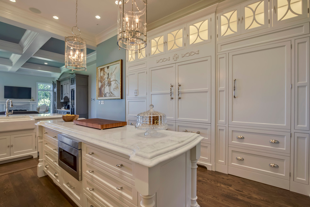 Open concept kitchen - huge transitional medium tone wood floor open concept kitchen idea with a farmhouse sink, beaded inset cabinets, white cabinets, marble countertops, white backsplash, ceramic backsplash, paneled appliances and an island