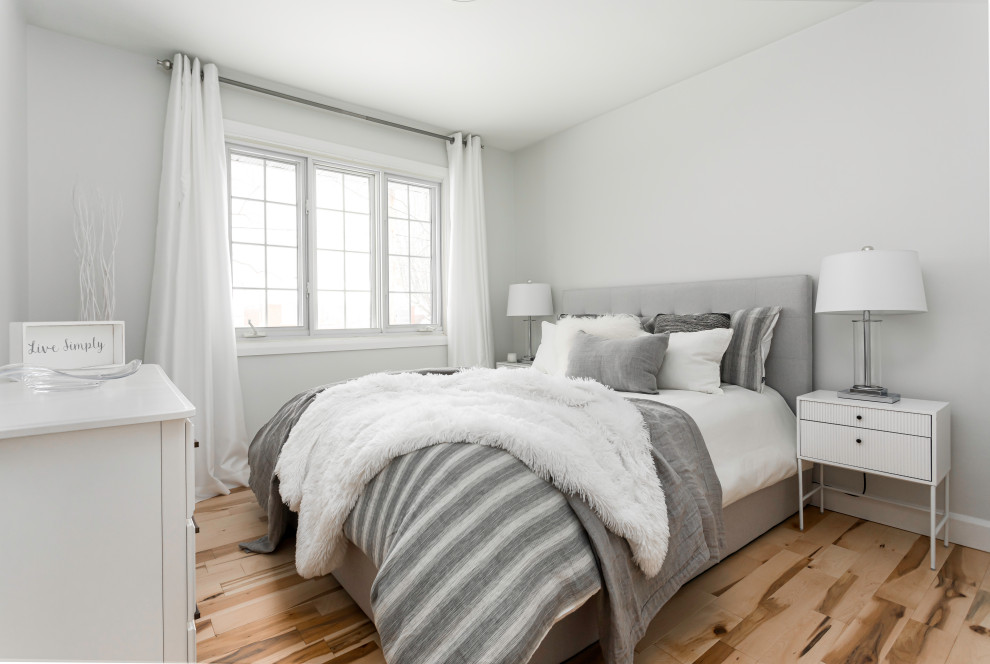 Modelo de dormitorio principal campestre pequeño con paredes blancas, suelo de madera clara y suelo marrón