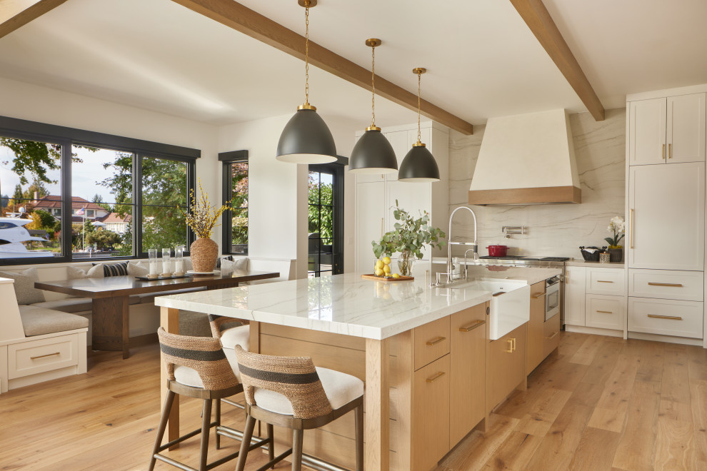 Inspiration for a country l-shaped eat-in kitchen in Seattle with a farmhouse sink, shaker cabinets, white cabinets, white splashback, panelled appliances, medium hardwood floors, with island, brown floor, white benchtop and exposed beam.