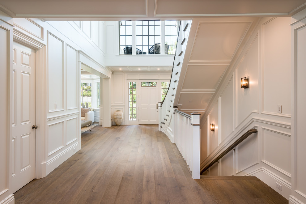 Photo of a large traditional foyer in Los Angeles with white walls, medium hardwood floors, a single front door, a white front door, beige floor, coffered and decorative wall panelling.