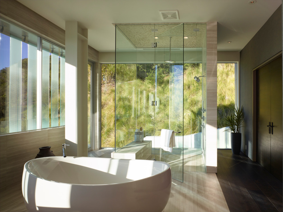 This is an example of an expansive modern master bathroom in Los Angeles with a freestanding tub, a curbless shower, brown tile, marble, marble floors, brown floor and a hinged shower door.