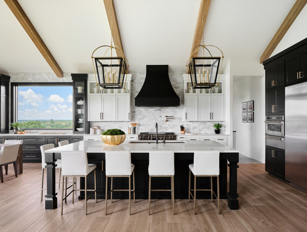 Expansive rural l-shaped open plan kitchen in Omaha with a submerged sink, shaker cabinets, black cabinets, engineered stone countertops, grey splashback, marble splashback, stainless steel appliances, porcelain flooring, an island, beige floors, white worktops and a vaulted ceiling.
