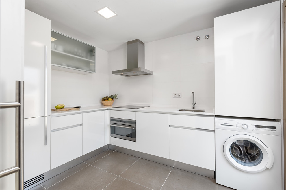 Photo of a mid-sized contemporary l-shaped separate kitchen in Malaga with an undermount sink, flat-panel cabinets, white cabinets, solid surface benchtops, white splashback, stainless steel appliances, ceramic floors and no island.