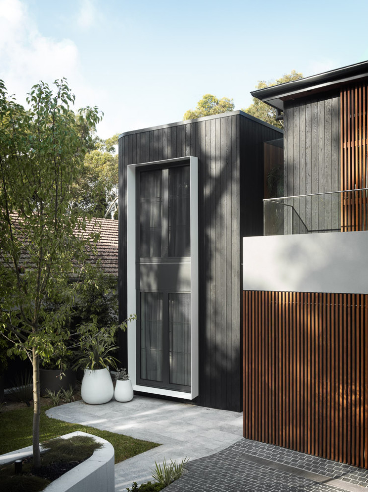 Design ideas for an expansive contemporary three-storey black house exterior in Sydney with wood siding, a hip roof, a metal roof, a black roof and board and batten siding.