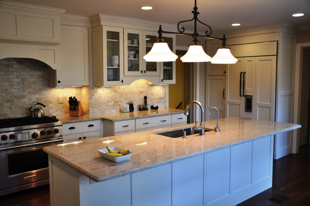 Transitional galley dark wood floor kitchen photo in New York with an undermount sink, shaker cabinets, white cabinets, granite countertops, beige backsplash, stone tile backsplash, stainless steel appliances and an island
