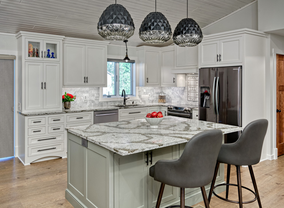 Design ideas for a mid-sized transitional l-shaped eat-in kitchen in Minneapolis with white cabinets, quartzite benchtops, white splashback, marble splashback, black appliances, vinyl floors, with island, brown floor, grey benchtop, an undermount sink and shaker cabinets.