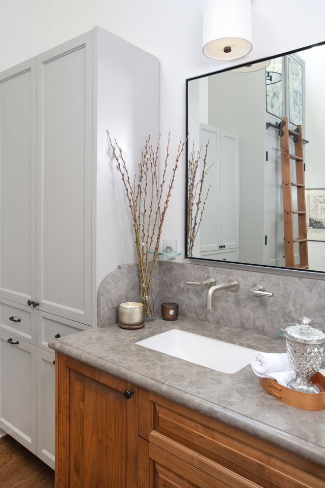 Design ideas for a transitional bathroom in Santa Barbara with an undermount sink, raised-panel cabinets, medium wood cabinets, white walls, medium hardwood floors and grey benchtops.