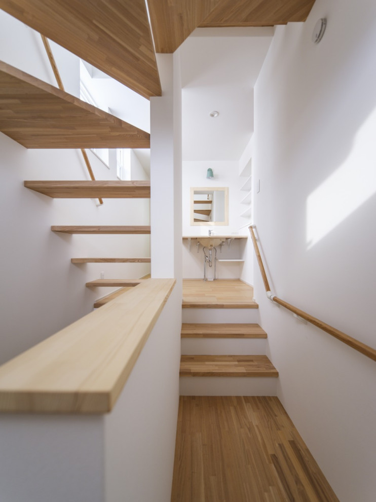 Cette image montre un escalier courbe nordique de taille moyenne avec des marches en bois, des contremarches en bois, un garde-corps en bois, du papier peint et palier.