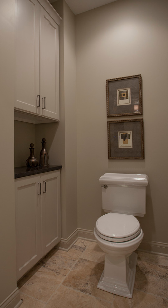 Idée de décoration pour un grand WC et toilettes tradition avec des portes de placard beiges, WC à poser, un carrelage beige, un carrelage de pierre, un mur beige, un sol en travertin, un lavabo encastré et un plan de toilette en quartz.