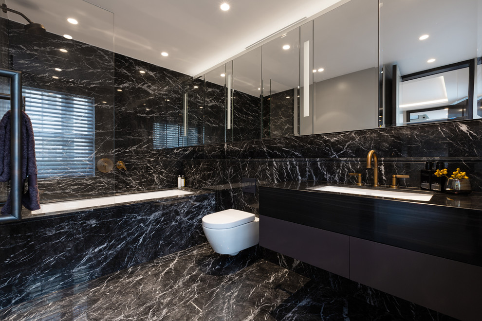 Photo of a contemporary master bathroom in London with flat-panel cabinets, black cabinets, an undermount tub, an open shower, a wall-mount toilet, black tile, stone slab, black walls, an undermount sink, black floor and an open shower.