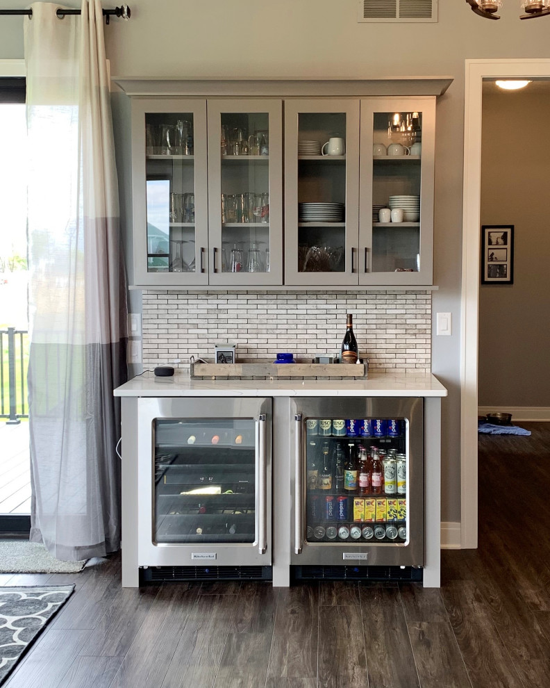 Large country l-shaped home bar in Other with flat-panel cabinets, grey cabinets, quartz benchtops, metal splashback, vinyl floors, brown floor and white benchtop.