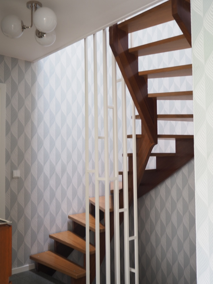 Gewendelte, Kleine Mid-Century Holztreppe mit offenen Setzstufen, Stahlgeländer und Tapetenwänden in München