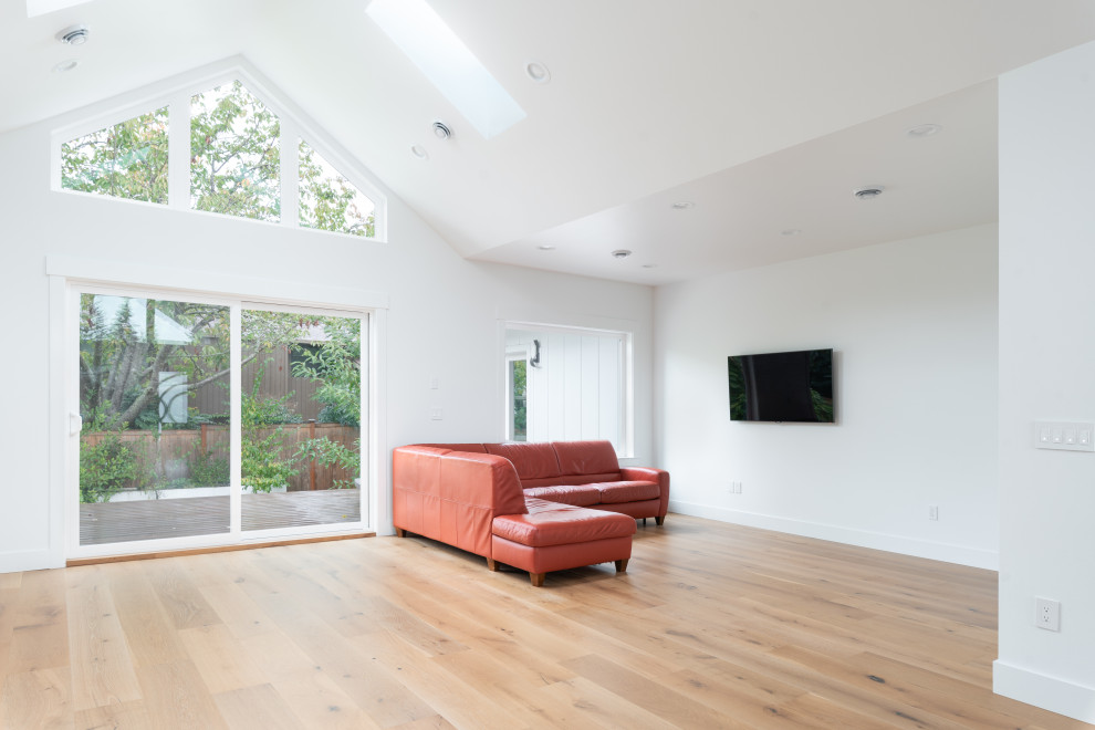 Imagen de salón abierto escandinavo extra grande con paredes blancas, suelo de madera clara, televisor independiente y suelo beige