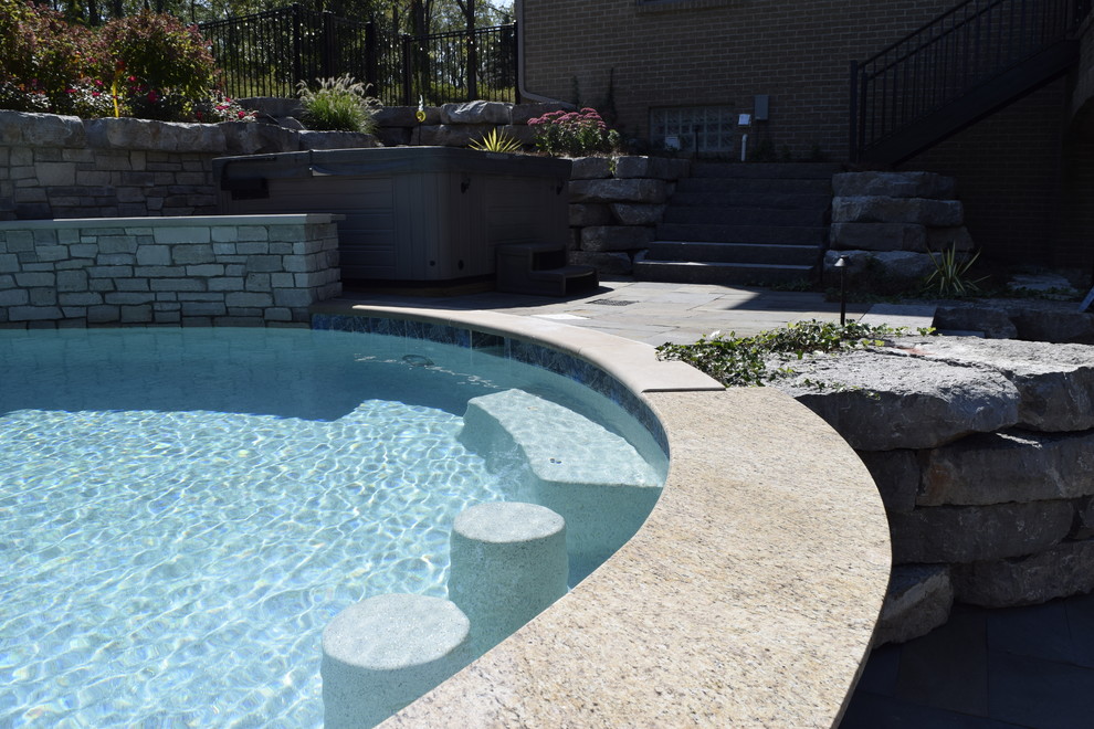 Design ideas for a large transitional backyard custom-shaped pool in Detroit with a water slide and natural stone pavers.
