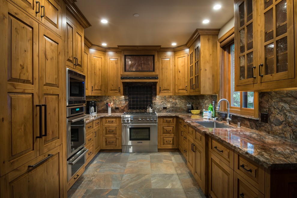 Mid-sized mountain style u-shaped slate floor and gray floor open concept kitchen photo with an undermount sink, raised-panel cabinets, medium tone wood cabinets, quartzite countertops, black backsplash, ceramic backsplash, stainless steel appliances, no island and brown countertops