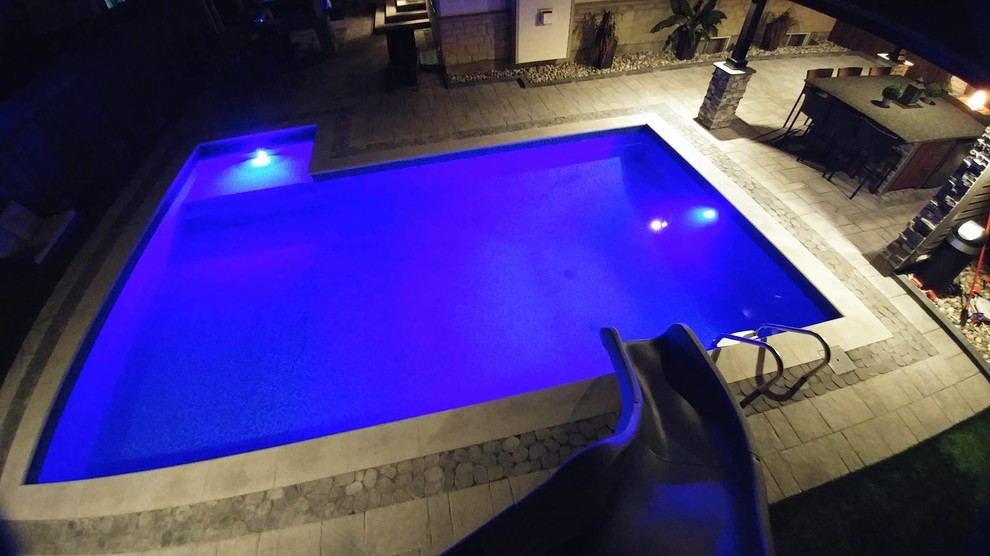 Mid-sized traditional backyard rectangular pool in Ottawa with a water slide and concrete pavers.