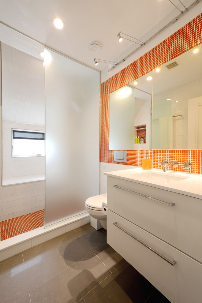 Contemporary bathroom in New York with an undermount sink, flat-panel cabinets, white cabinets, an alcove shower, orange tile, mosaic tile and slate floors.