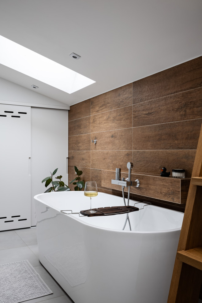 Inredning av ett nordiskt mellanstort badrum, med ett fristående badkar, brun kakel, porslinskakel, klinkergolv i porslin och grått golv