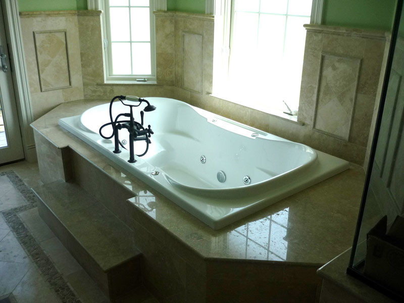 Example of a marble floor bathroom design in Miami with a hot tub and beige walls