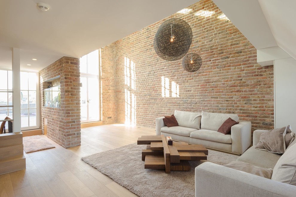 This is an example of a large industrial loft-style family room in Cologne with multi-coloured walls, light hardwood floors, no fireplace, no tv and brown floor.