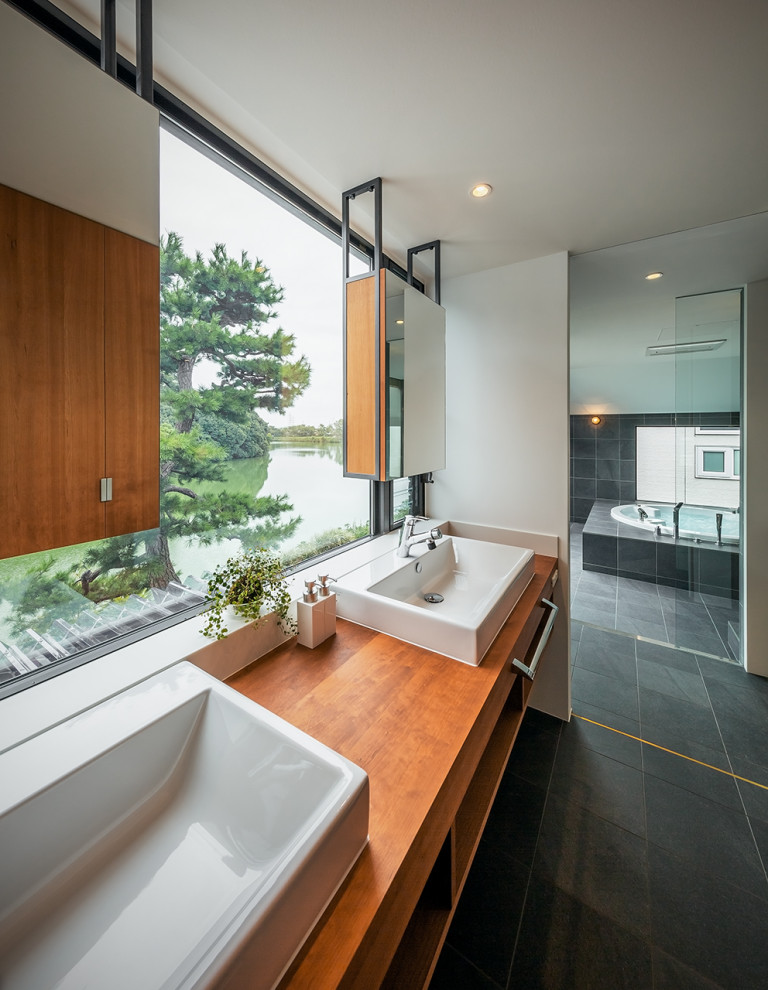 This is an example of a contemporary bathroom in Osaka with marble floors, wood benchtops, black floor, a double vanity, timber, planked wall panelling, white cabinets, a hot tub, a double shower and a built-in vanity.