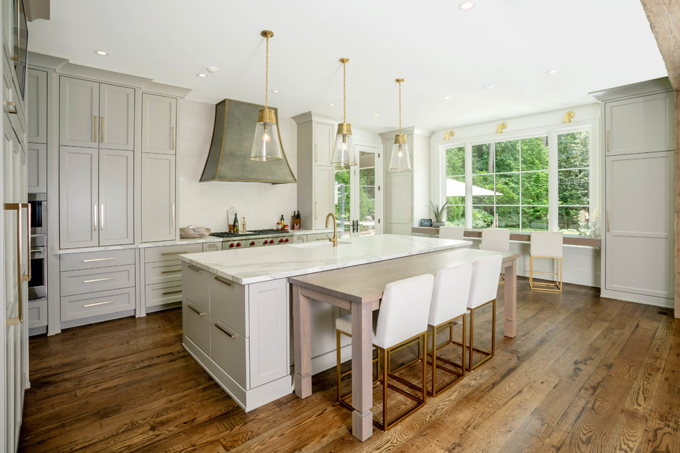Kitchen - transitional l-shaped medium tone wood floor and brown floor kitchen idea in Atlanta with an undermount sink, shaker cabinets, gray cabinets, white backsplash, an island and white countertops