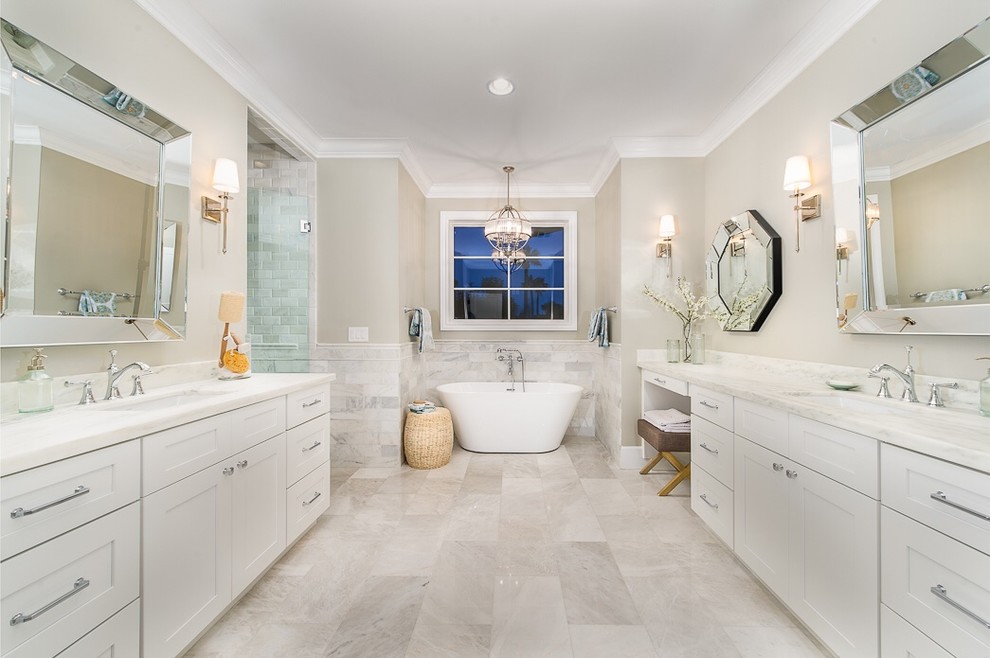 This is an example of a large transitional master bathroom in Phoenix with recessed-panel cabinets, white cabinets, a freestanding tub, an alcove shower, stone tile, beige walls, an undermount sink and a hinged shower door.