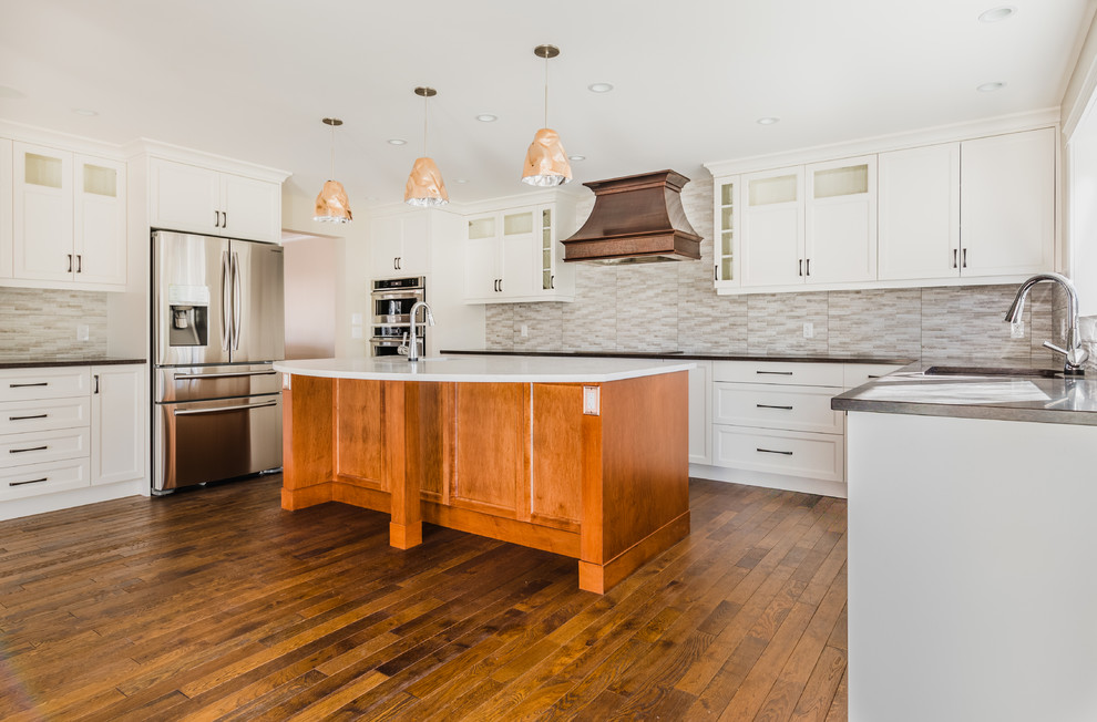 Inspiration for a mid-sized transitional u-shaped medium tone wood floor open concept kitchen remodel in Calgary with an undermount sink, recessed-panel cabinets, white cabinets, quartz countertops, gray backsplash, ceramic backsplash, stainless steel appliances and an island