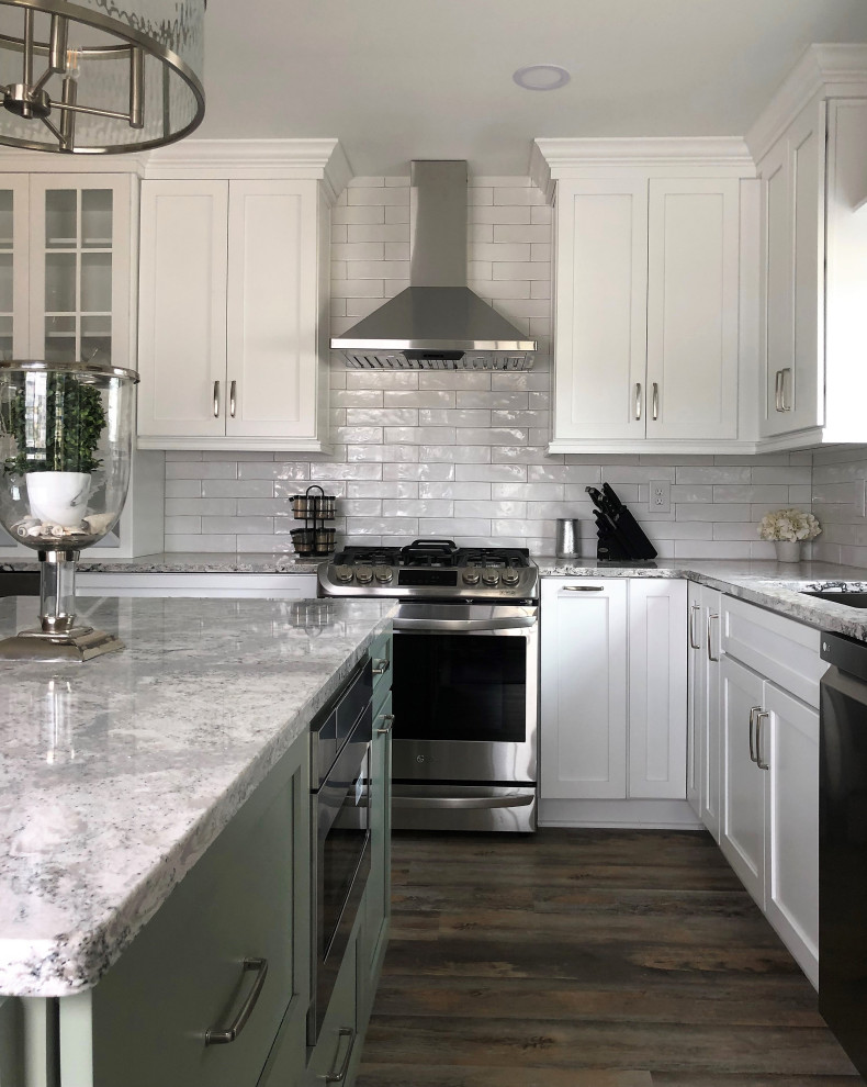 Example of a mid-sized transitional l-shaped vinyl floor and multicolored floor eat-in kitchen design with an undermount sink, flat-panel cabinets, green cabinets, quartz countertops, white backsplash, ceramic backsplash, stainless steel appliances, an island and gray countertops