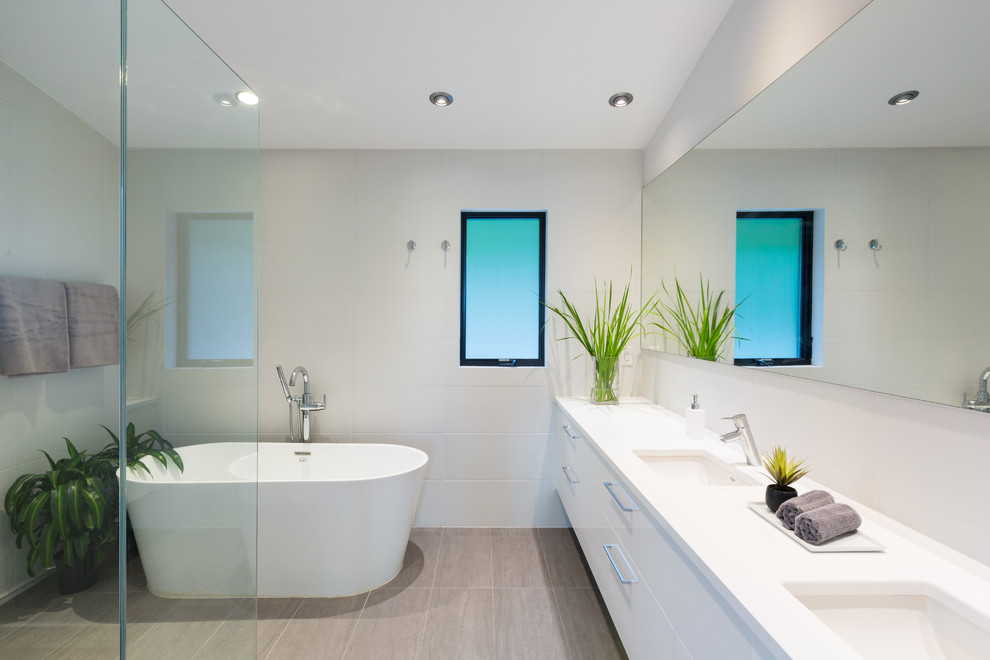 Mid-sized contemporary master bathroom in Vancouver with flat-panel cabinets, white cabinets, a freestanding tub, white tile, white walls, porcelain floors, an undermount sink and engineered quartz benchtops.