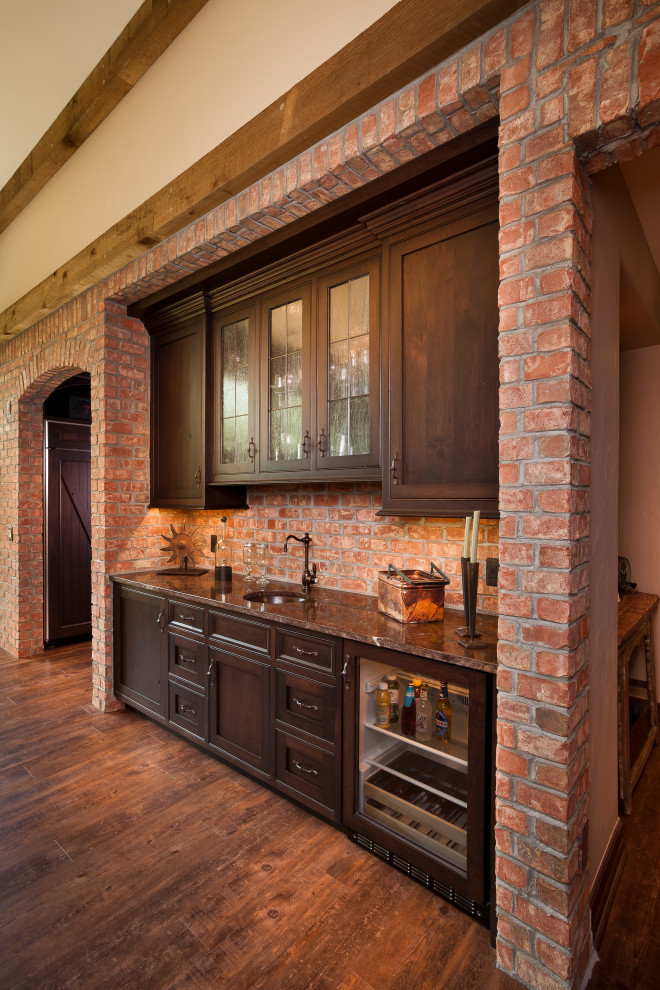 Mid-sized country single-wall wet bar in Detroit with an undermount sink, shaker cabinets, dark wood cabinets, red splashback, brick splashback, medium hardwood floors, brown floor and brown benchtop.