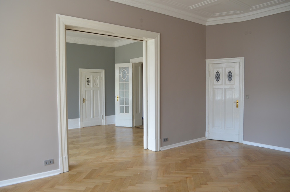 Klassisk inredning av ett stort allrum med öppen planlösning, med en hemmabar, beige väggar, ljust trägolv och brunt golv