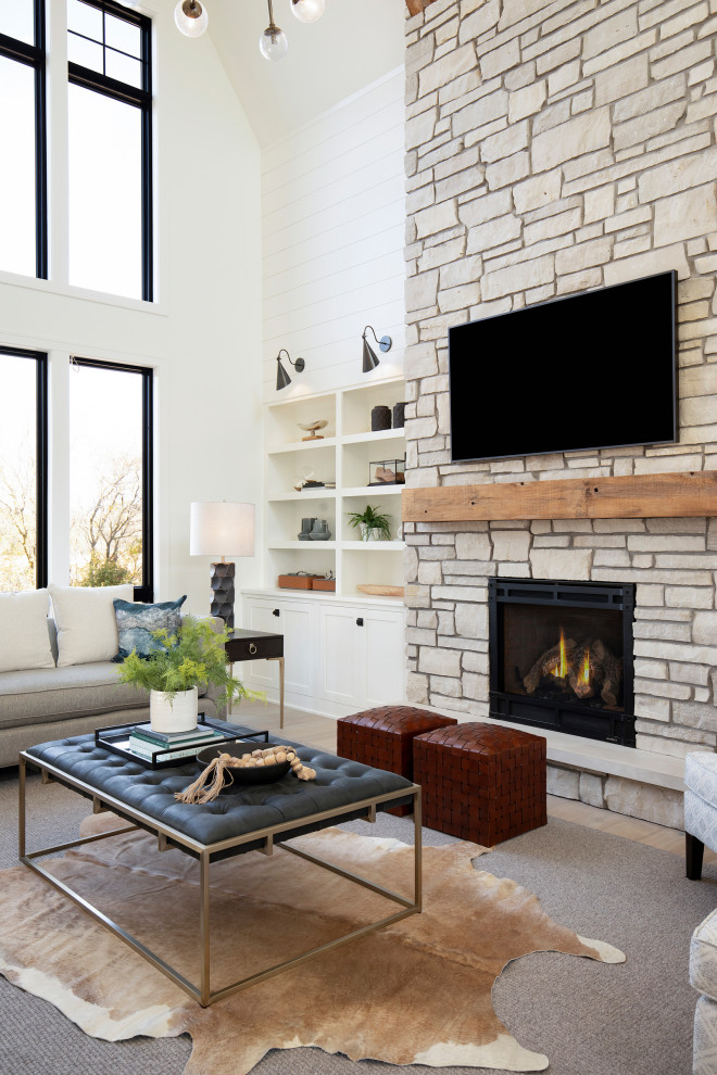 Expansive transitional open concept living room in Minneapolis with white walls, light hardwood floors, a standard fireplace, a stone fireplace surround, a built-in media wall, beige floor, vaulted and planked wall panelling.