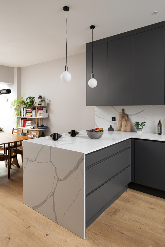 This is an example of a small modern u-shaped kitchen in London with grey cabinets, quartz worktops, white splashback and white worktops.